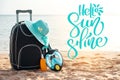 Phrase Hello Sunshine and Suitcase wiht hat, sunscreen with a mask. The tropical sea, beach in the background. The