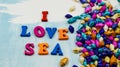 The phrase `I love sea` is composed of colorful wooden letters on a blue and white background and colorful shells. Royalty Free Stock Photo