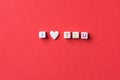 Phrase I Love You Made from Letter Cubes and Single Heart Shape White Sugar Candy Sprinkle on Dark Red Background. Valentines Royalty Free Stock Photo