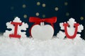 Phrase I Love You made of paper letters and festive heart shaped ornament on snow against blue background Royalty Free Stock Photo