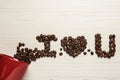 Phrase I Love You made of scattered coffee beans from red cup on white wooden table, flat lay Royalty Free Stock Photo