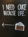 Phrase `I need cake because life` on advertising black board on the street.