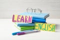 Phrase LEARN ENGLISH, books, glasses and felt tip pens on white table