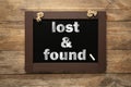 Phrase Lost and Found written on blackboard on wooden table, top view