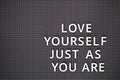 Phrase Love Yourself Just As You Are spelled out with white letters on gray pegboard