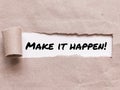 Phrase MAKE IT HAPPEN appearing behind torn brown paper. Royalty Free Stock Photo