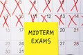 The phrase Midterm exams written on a yellow sticky note posted on a calendar or planner page as a reminder. Closeup of a personal