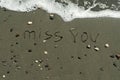 Words Miss You on beach sand beside sea wave Royalty Free Stock Photo