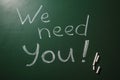 Phrase `We need you` written on green chalkboard, top view. Royalty Free Stock Photo