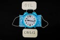 Phrase OIL Crisis and Disposable mask with clock on black background. Down of oil price, market decline. Financial world crisis co