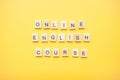 Phrase online english course made from wooden blocks on a light yellow background