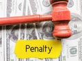 Phrase penalty written on yellow paper strip with gavel and fake money.
