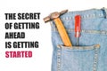 Phrase THE SECRET OF GETTING AHEAD IS GETTING STARTED written over white background with hammer, screwdriver and blue jeans Royalty Free Stock Photo