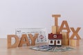 Phrase TAX DAY, wooden cubes, house model, calendar and money on table against light background Royalty Free Stock Photo