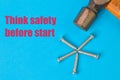 Phrase THINK SAFETY BEFORE STARTED written on a blue background with hammer and bunch of screws