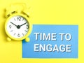 Phrase TIME TO ENGAGE written on blue card with alarm clock over yellow background. Royalty Free Stock Photo