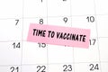 The phrase Time to Vaccinate written on a pink sticky note posted on a calendar or planner page. Deadline concept read a reminder Royalty Free Stock Photo