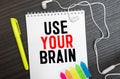 The phrase Use Your Brain in blue text on an index card pinned to a cork notice board as a reminder Royalty Free Stock Photo