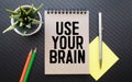 The phrase Use Your Brain in blue text on an index card pinned to a cork notice board as a reminder Royalty Free Stock Photo