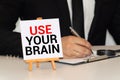 The phrase Use Your Brain in blue text on an index card pinned to a cork notice board as a reminder Royalty Free Stock Photo