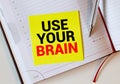 The phrase Use Your Brain in blue text on an index card pinned to a cork notice board as a reminder Royalty Free Stock Photo