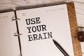 The phrase Use Your Brain in blue text on an index card pinned to a cork notice board as a reminder Royalty Free Stock Photo