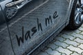 Phrase Wash Me written on dirty car, closeup Royalty Free Stock Photo