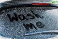 Phrase Wash Me written on dirty car window, closeup Royalty Free Stock Photo