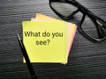 Phrase what do you see written on sticky note with a pen and eye glasses.