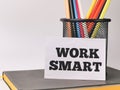 Phrase WORK SMART written on paper note with colorful pencil and a book. Royalty Free Stock Photo