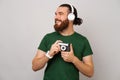 Phto of happy bearded hipster man in green t-shirt holdling old vintage camera and looking away over gray background Royalty Free Stock Photo