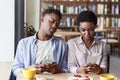 Phubbing problem. Black couple stuck in their smartphones on boring date at cafe Royalty Free Stock Photo