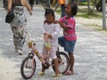 Phuket, Phuket Thailand - 10 15 2012: dark-skinned Asian girl holds her friend by the shoulders who is busy with her bike