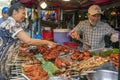 Phuket, Thailand, January 8, 2020: A woman chooses the best pieces of fried chicken from a fast food street vendor in