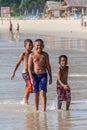 Local Asian children on the beach. Three boys playing in the waves. Royalty Free Stock Photo