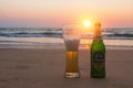 Phuket, Thailand - Mart 12, 2019: misted bottle and glass of cold Chang beer on the sand at the background of seascape, sunset sky Royalty Free Stock Photo