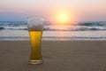 Misted glass of cold Chang beer on the sand at the background of seascape, sunset sky and sea waves Royalty Free Stock Photo