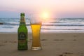 Phuket, Thailand - Mart 12, 2019: misted bottle and glass of cold Chang beer on the beach at background of seascape, sunset sky Royalty Free Stock Photo