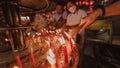 PHUKET, THAILAND - SEPTEMBER 24, 2022: Hand holding to light the red incense with flame of candle in the temple. Ritual, belief an