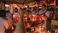 PHUKET, THAILAND - SEPTEMBER 24, 2022: Hand holding to light the red incense with flame of candle in the temple. Ritual, belief an