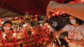 PHUKET, THAILAND - SEPTEMBER 24, 2022: Hand holding to light the red incense with flame of candle in the temple. Ritual, belief an