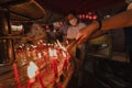 PHUKET, THAILAND - SEPTEMBER 24, 2022: Hand holding to light the red incense with flame of candle in the temple. Ritual, belief an