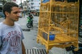 A young man standing by the wild songbirds in cages at the market. Travel around Asia.