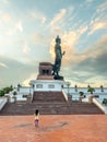 Phutthamonthon Buddha walking statue under evening cloudy sky in Thailand