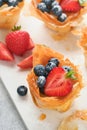 Phyllo or filo pies with fresh berries strawberries and blueberries, cheese filling topped with fresh mint on white plate. Home