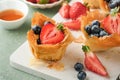 Phyllo or filo pies with fresh berries strawberries and blueberries, cheese filling topped with fresh mint on white plate. Home