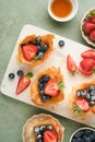 Phyllo or filo pies with fresh berries strawberries and blueberries, cheese filling topped with fresh mint on white plate.