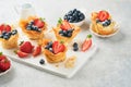 Phyllo or filo pies with fresh berries strawberries and blueberries, cheese filling topped with fresh mint on white plate.