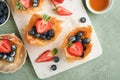 Phyllo or filo pies with fresh berries strawberries and blueberries, cheese filling topped with fresh mint on white plate.