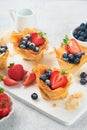 Phyllo or filo pies with fresh berries strawberries and blueberries, cheese filling topped with fresh mint on white plate. Hom